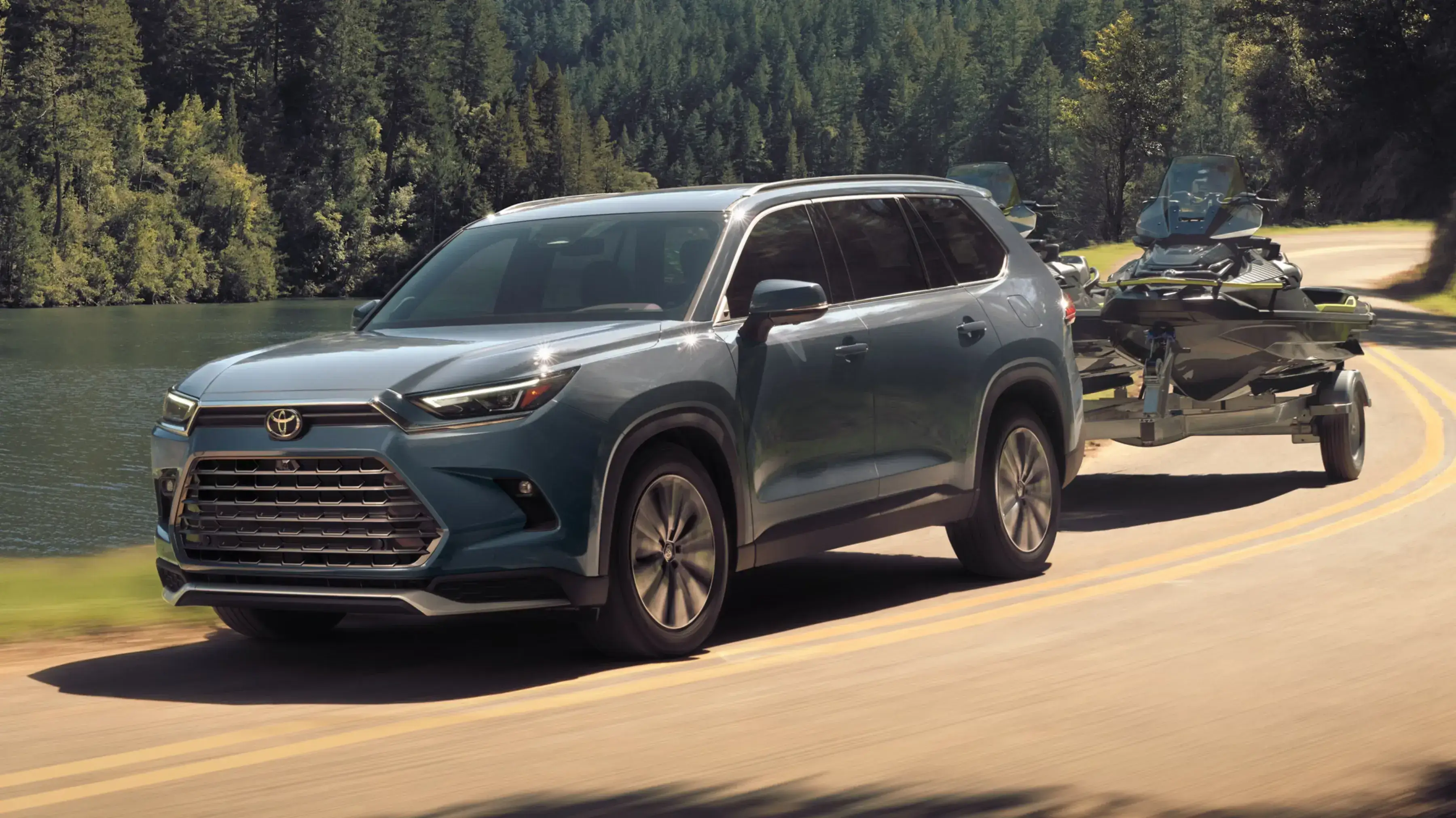 Toyota Grand Highlander in front three-quarter view towing a personal watercraft trailer, shown for Plaza Toyota in New York