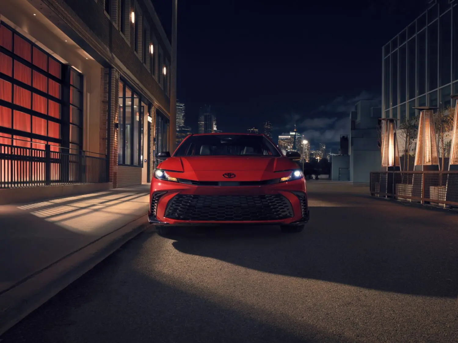 Red Toyota Camry on a city street at night, front view