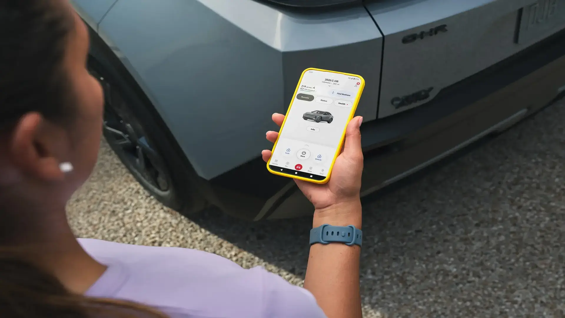 Driver using a smartphone to remotely check and schedule charging on the Toyota C-HR