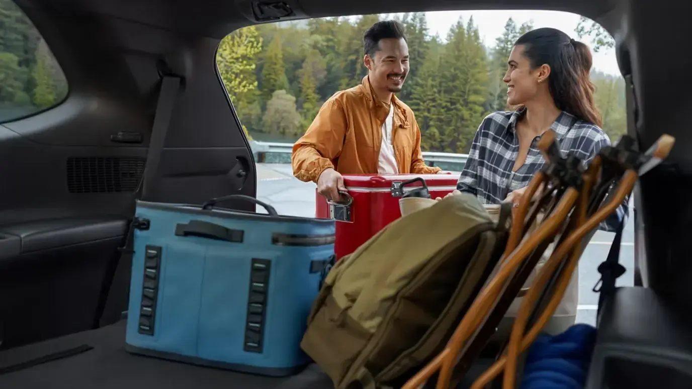 Couple loading a cooler and camping gear into the Toyota Grand Highlander cargo area