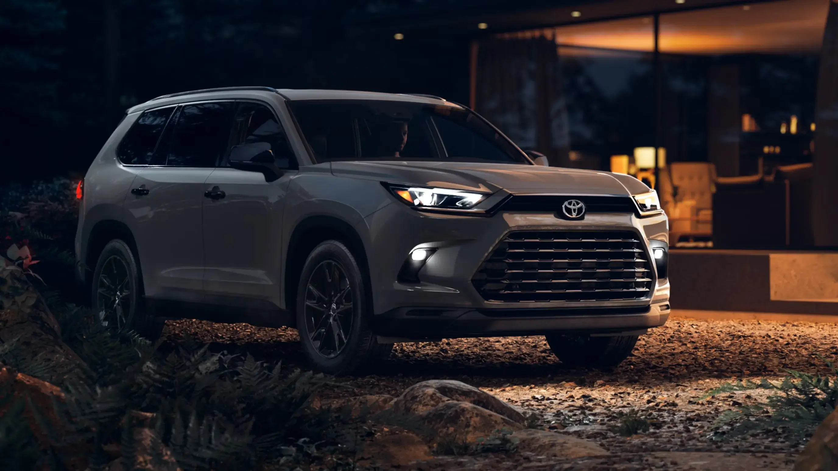 Gray Toyota Grand Highlander parked at night, front three-quarter view facing right