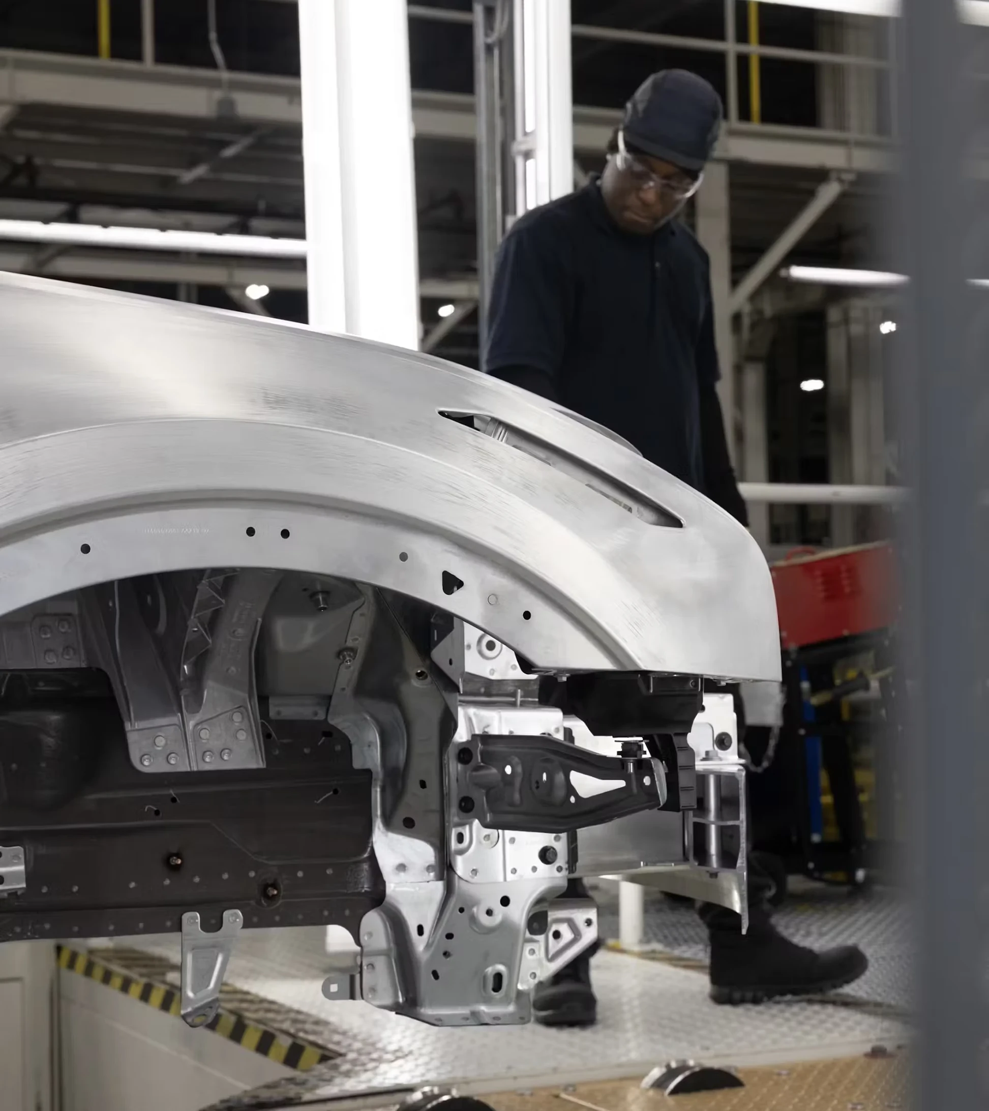 A Polestar 3 making it's way down the assembly line while being inspected by a worker