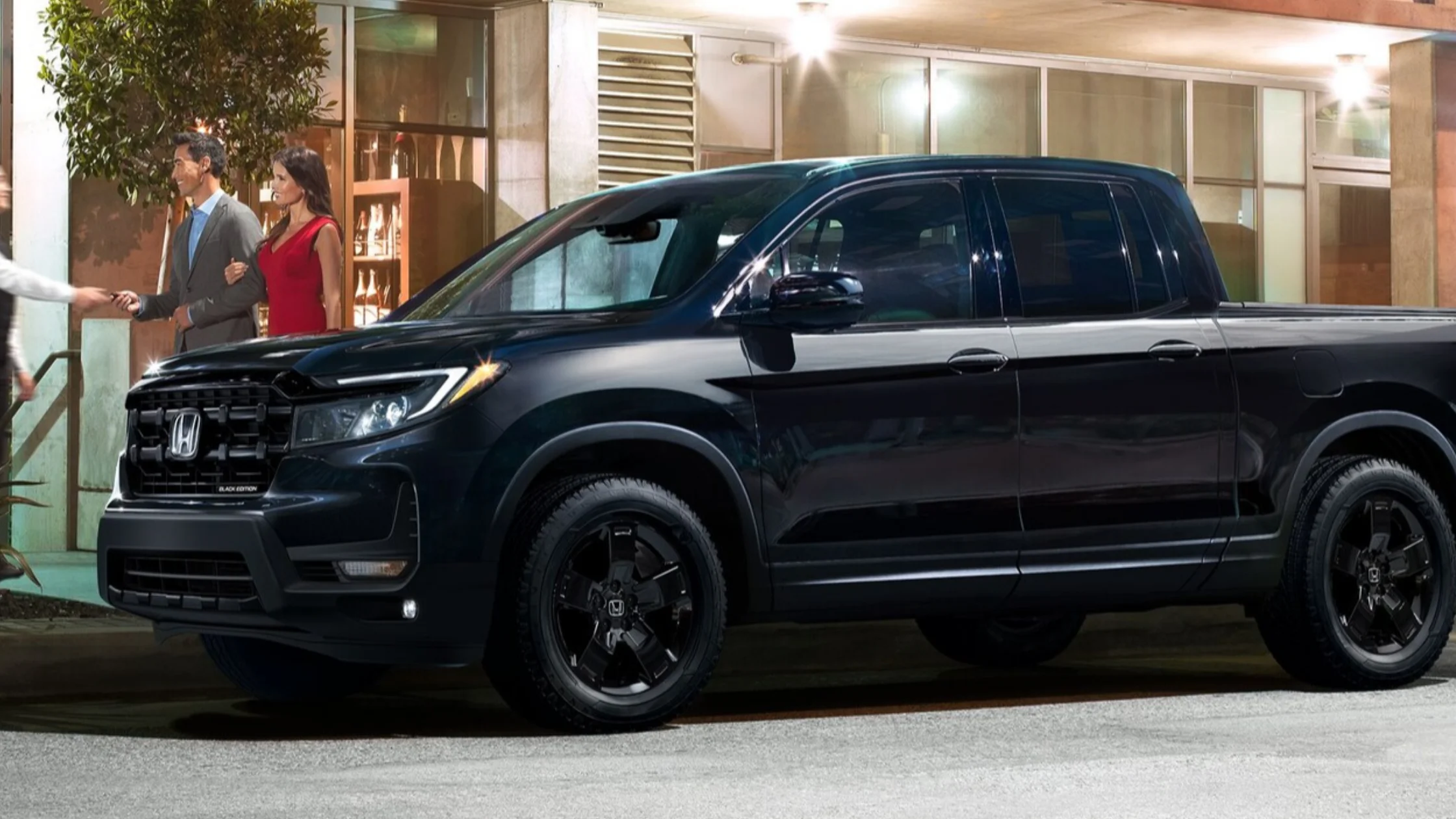 2026 Honda Ridgeline pickup near people arriving outside a lit entrance