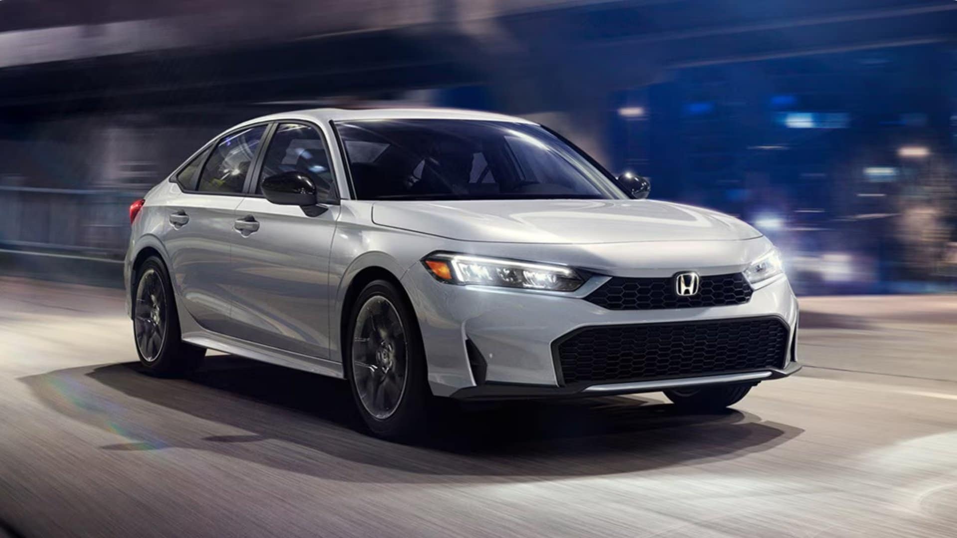 White 2026 Honda Civic Sedan driving through a city street at night with motion blur