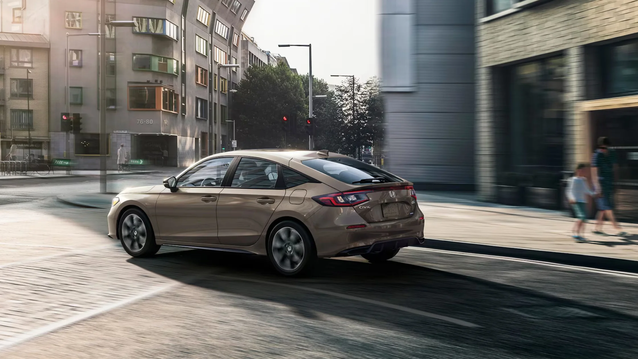 Side view of 2026 Honda Civic Hatchback Hybrid in beige, highlighting compact hybrid body and rear spoiler.