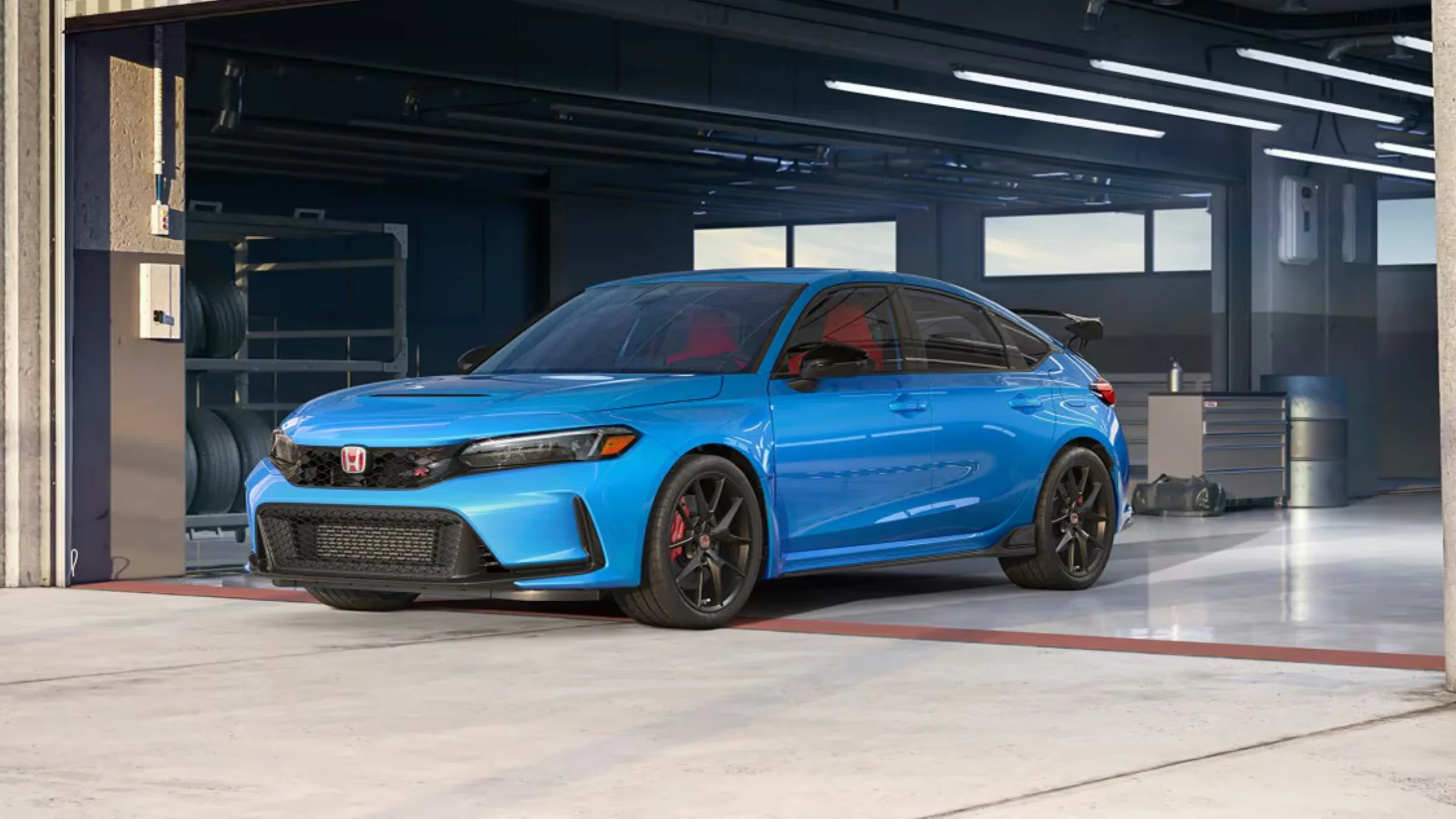 Front-side view of 2025 Honda Civic Type R in blue parked in a garage, highlighting sporty design and red interior accents.