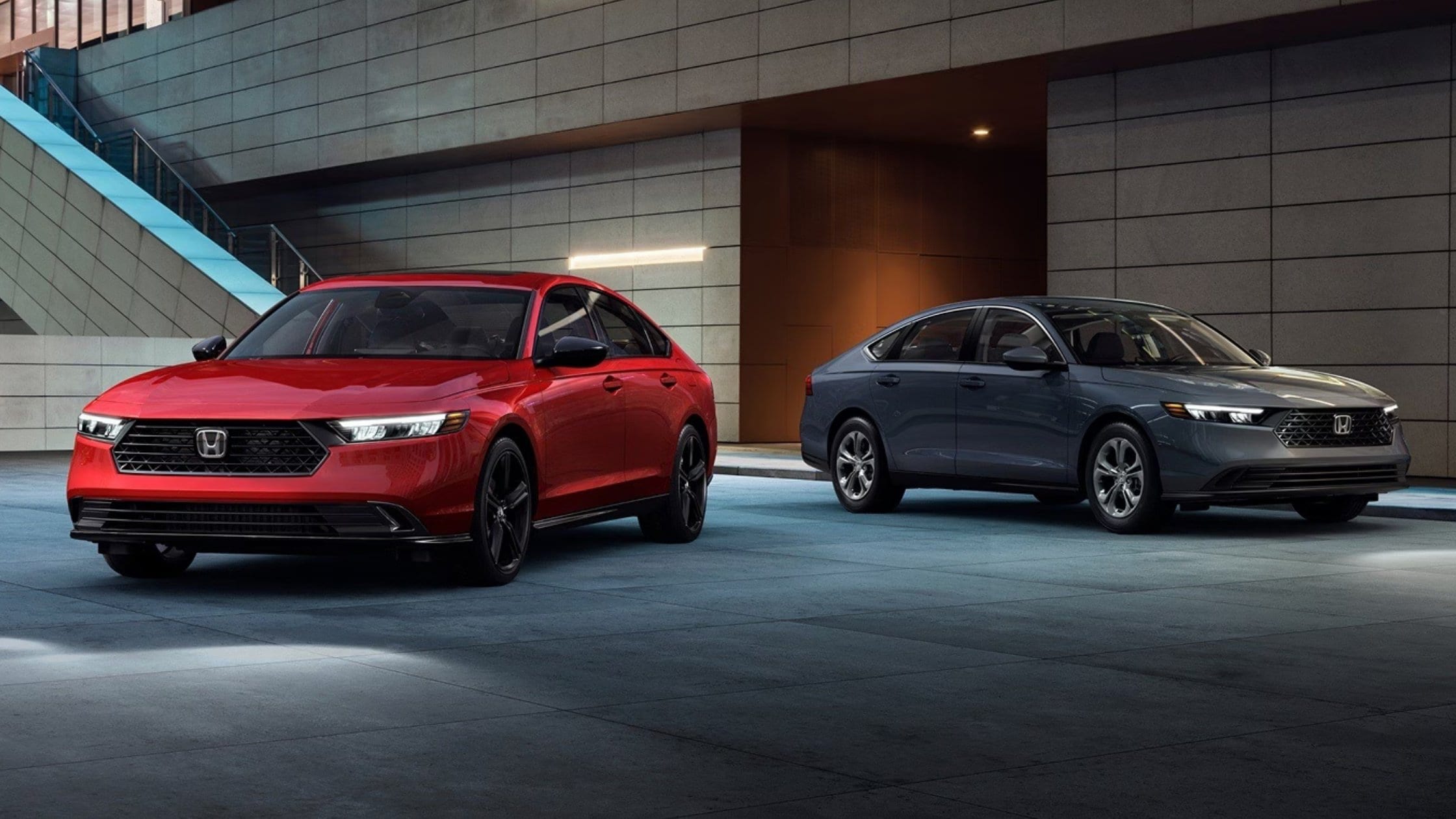 2026 Honda Accord sedans in red and gray parked outside of a modern building with LED headlights on.
