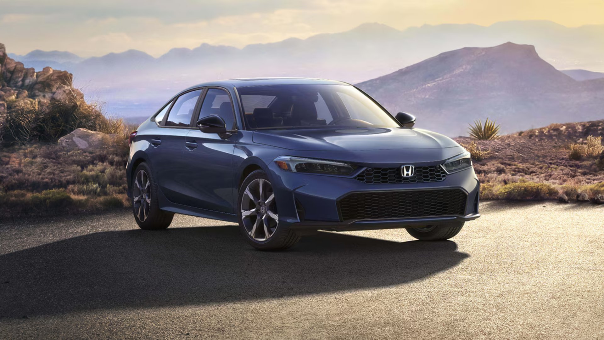Blue 2026 Honda Civic Sedan Hybrid parked on a scenic mountain overlook at sunset