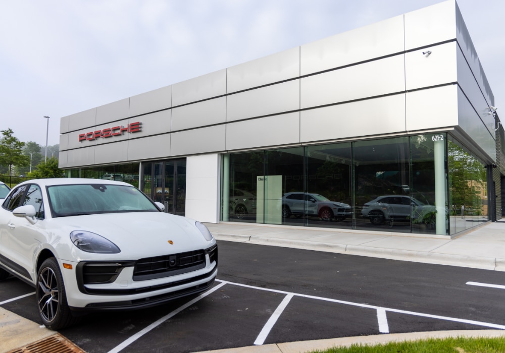 Porsche dealership storefront in Asheville, NC with a Porsche SUV parked in front