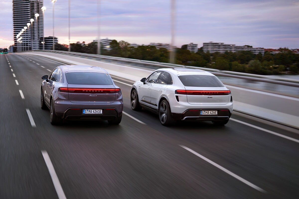 Two Porsche Macan Electric vehicles drive down the highway