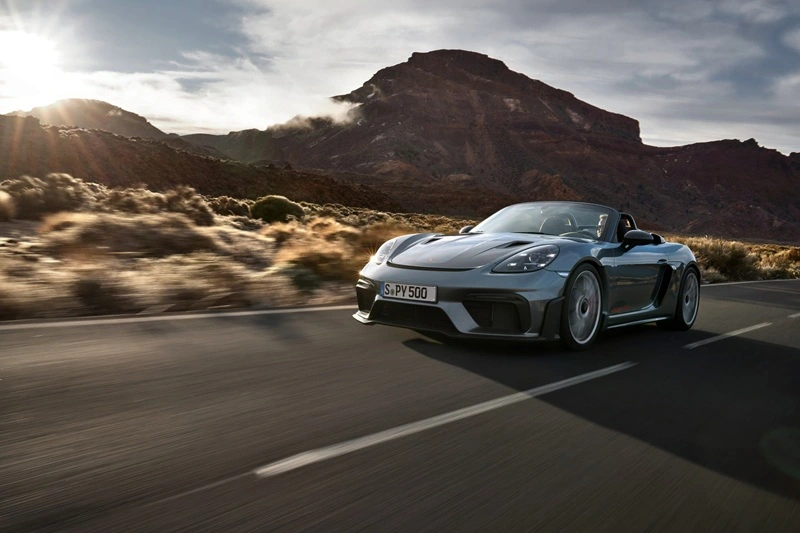 Grey Porsche 718 Boxster driving down street