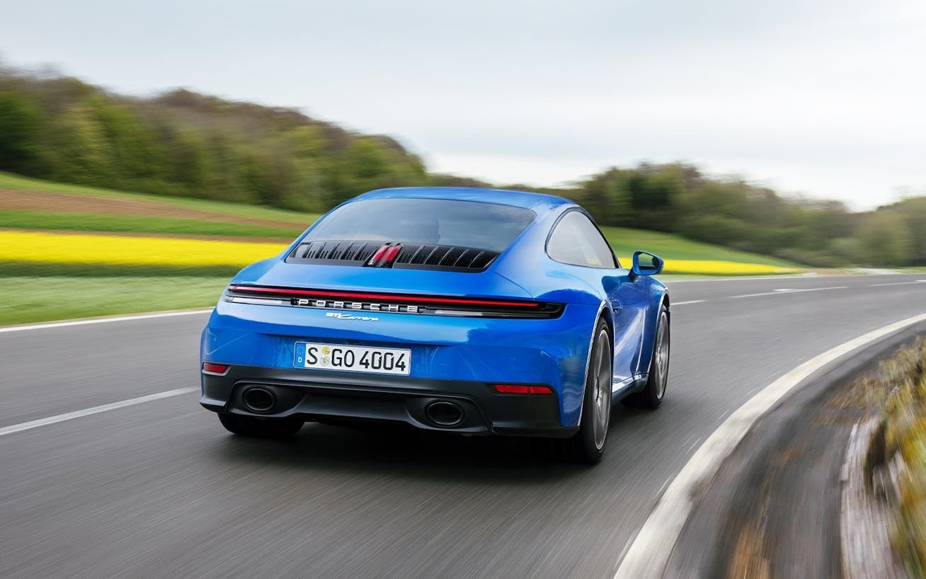 Blue Carrera S driving down a road.