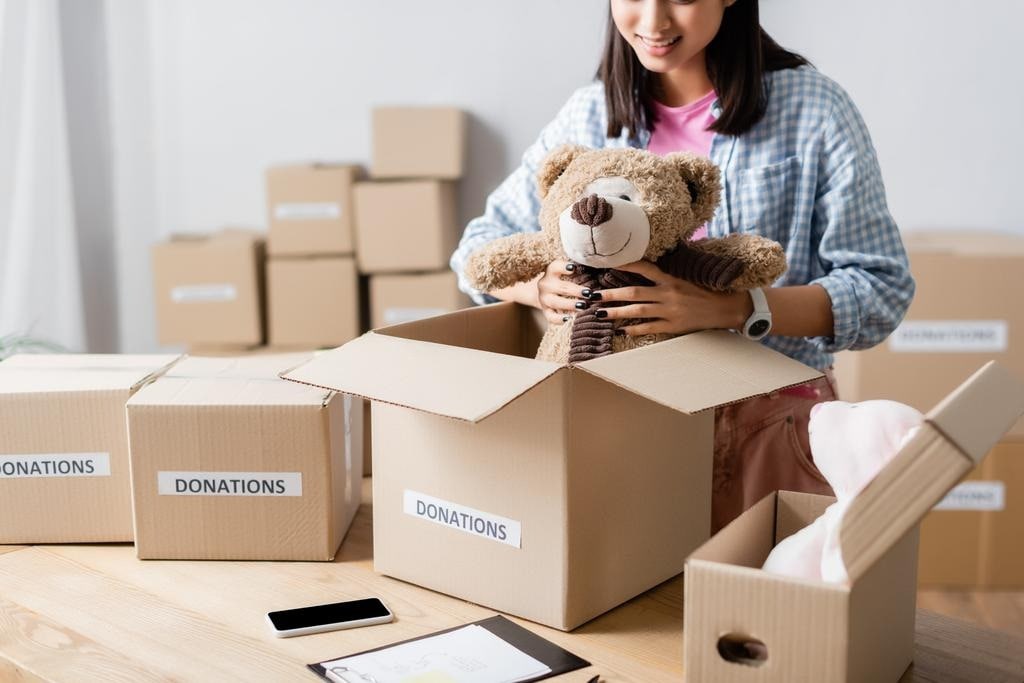 Woman placing a teddy bear into a donation box