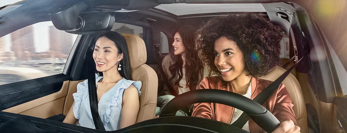 A group of three smiling women in a Porsche.