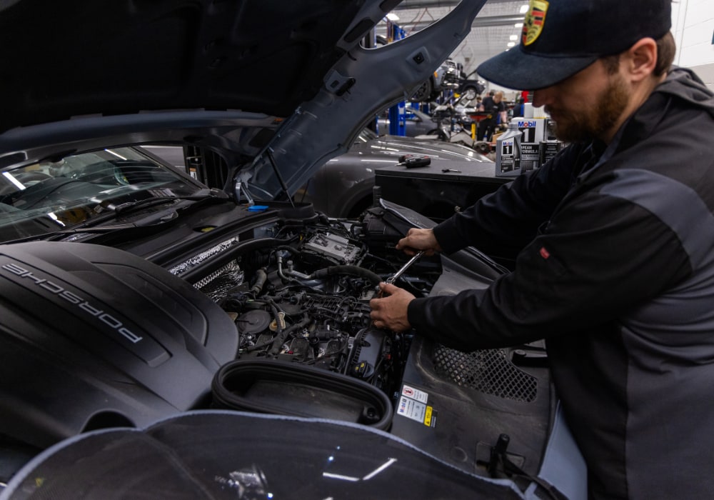 Porsche service technician working under the hood of a car at the Porsche Charlottesville service center