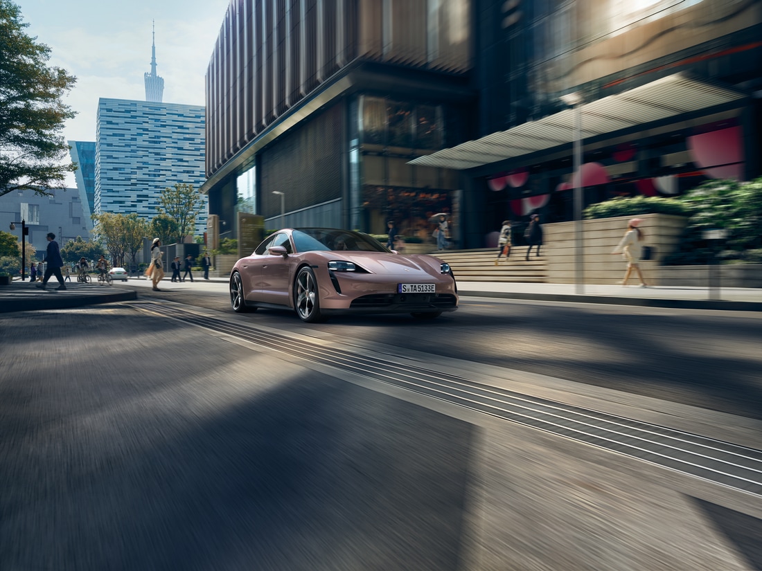 pink Porsche Taycan sports car sedan driving through a city