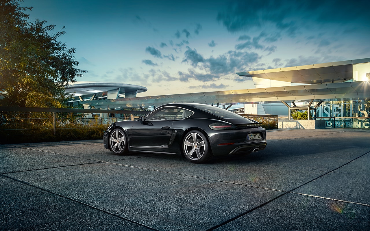 black Porsche 718 parked in front of a modern metal and cement building
