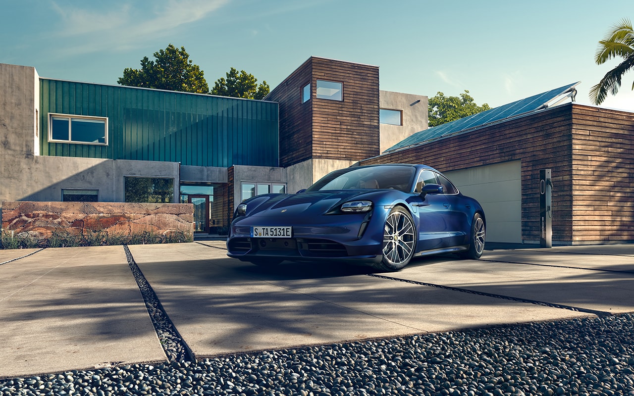 blue Porsche Taycan parked in the driveway of a modern home