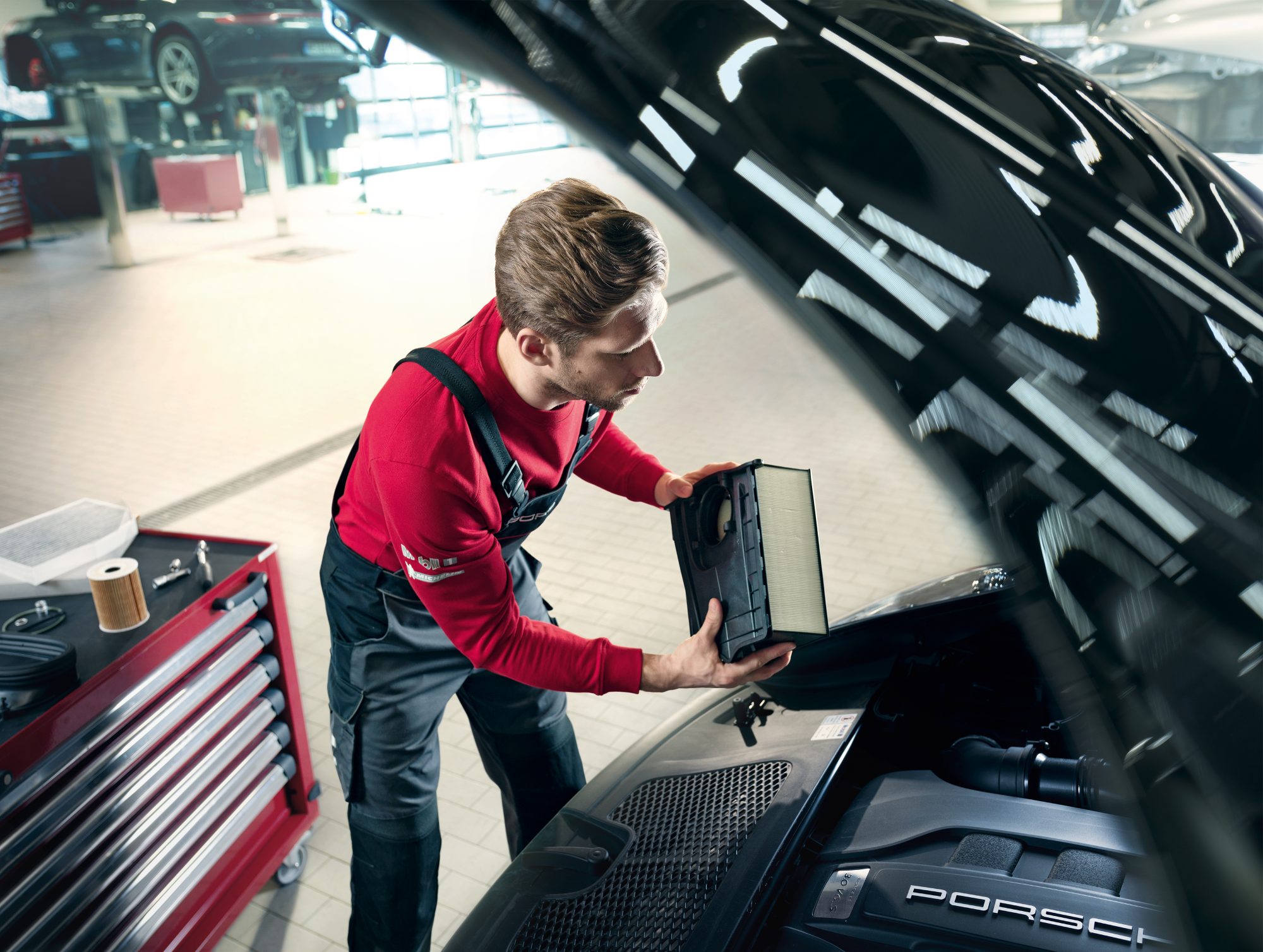 Technician changing battery with open engine