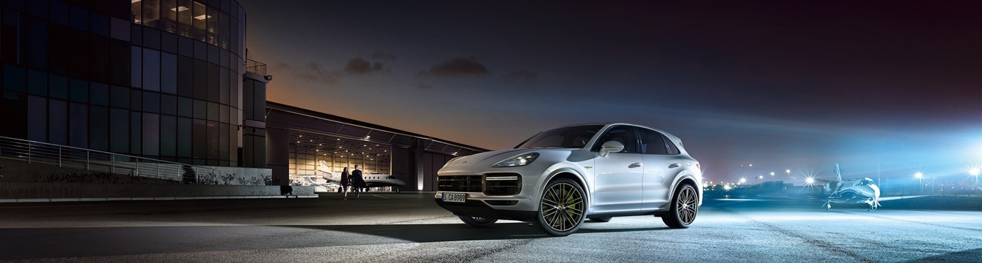 Porsche Cayenne E=Hybrid White Porsche Cayenne E-Hybrid parked at an airport at night