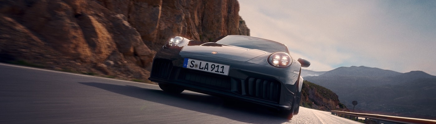 Blue Porsche 911 Carrera GTS driving on a road in the desert