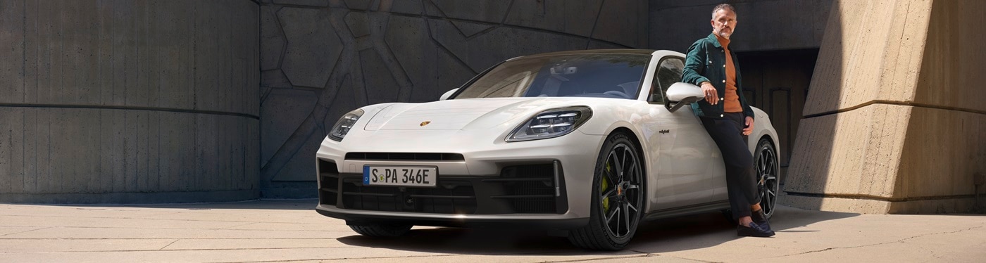 White Porsche Panamera E-Hybrid parked in front of a stone construct