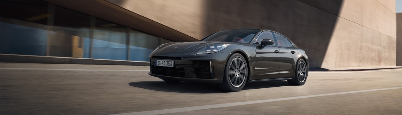 Grey Porsche Panamera 4 driving near a modern building