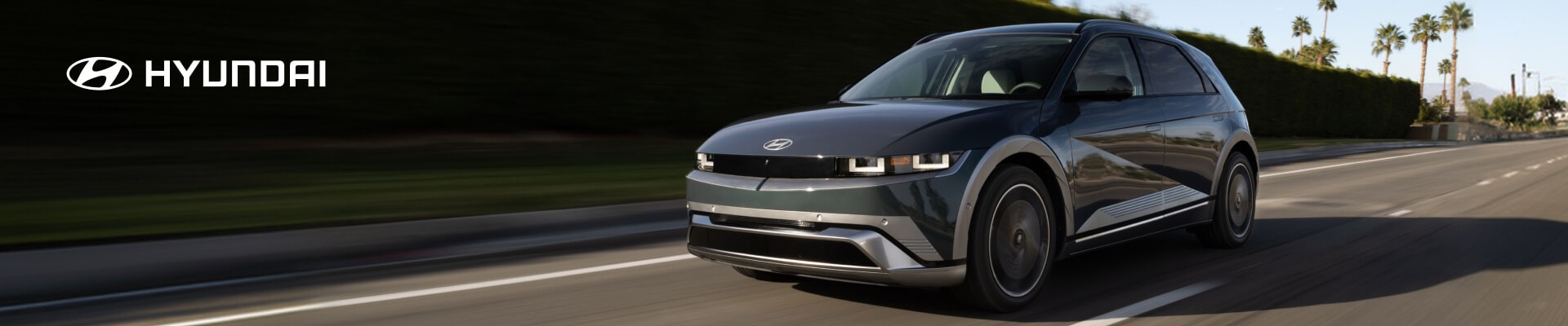 2026 Hyundai IONIQ 5 Limited in Digital Teal, front three-quarter view driving on a palm-lined road.