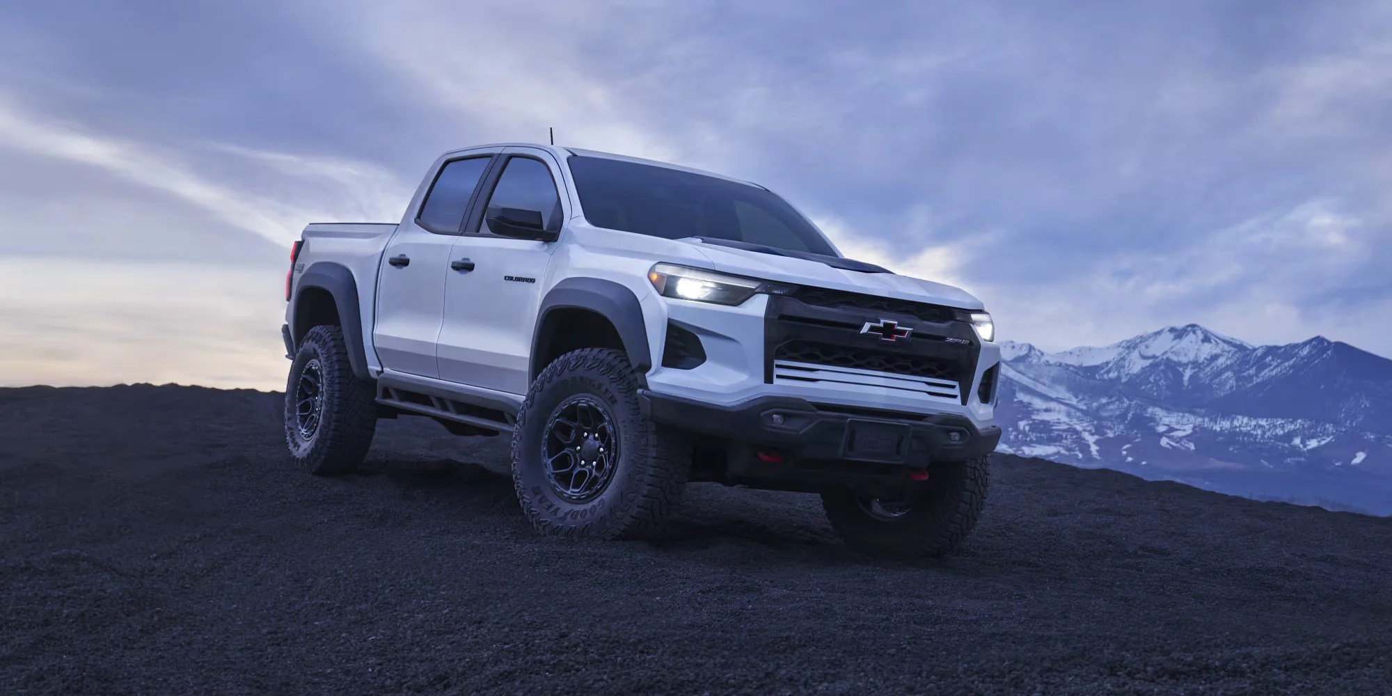 2026 Chevy Colorado in white, profile view with mountains behind, showing the truck's stance