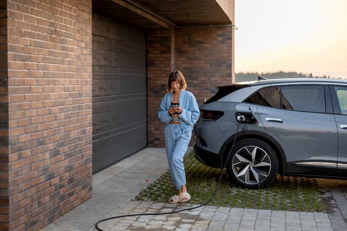 woman-charges-her-electric-car-near-a-house-2023-11-27-04-50-26-utc%20(2).jpg