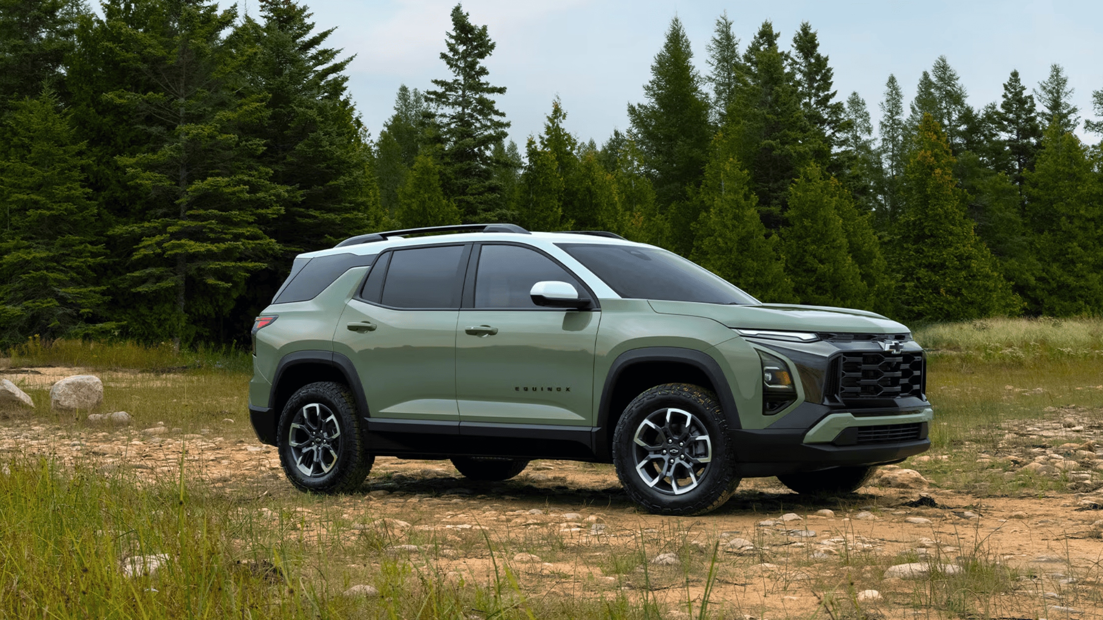 2025 Chevrolet Equinox in green parked on a rocky trail surrounded by trees, emphasizing its fuel efficiency and safety for Fayetteville buyers.