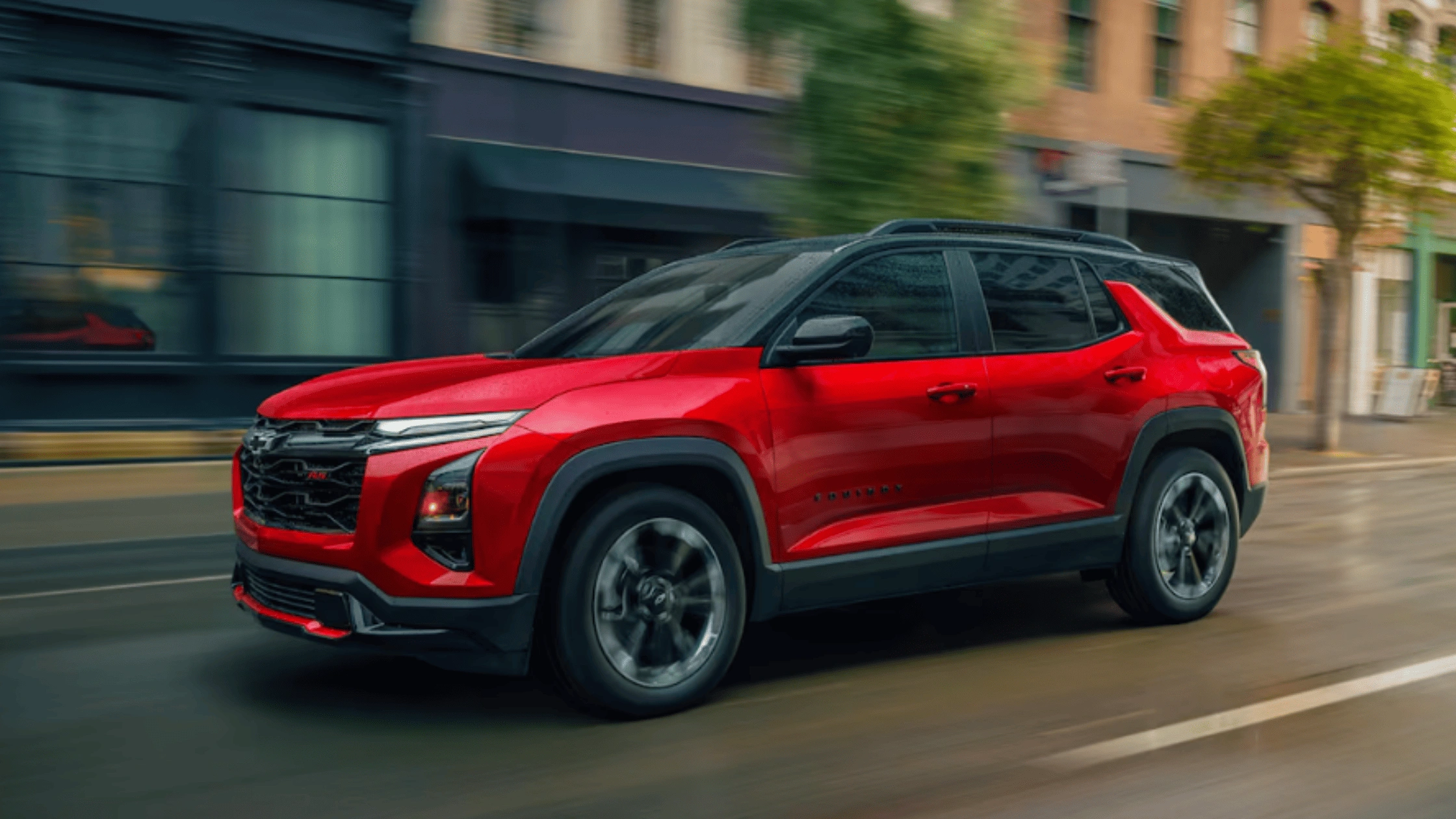 Red 2025 Chevrolet Equinox SUV driving through town, built for family safety in Fort Bragg