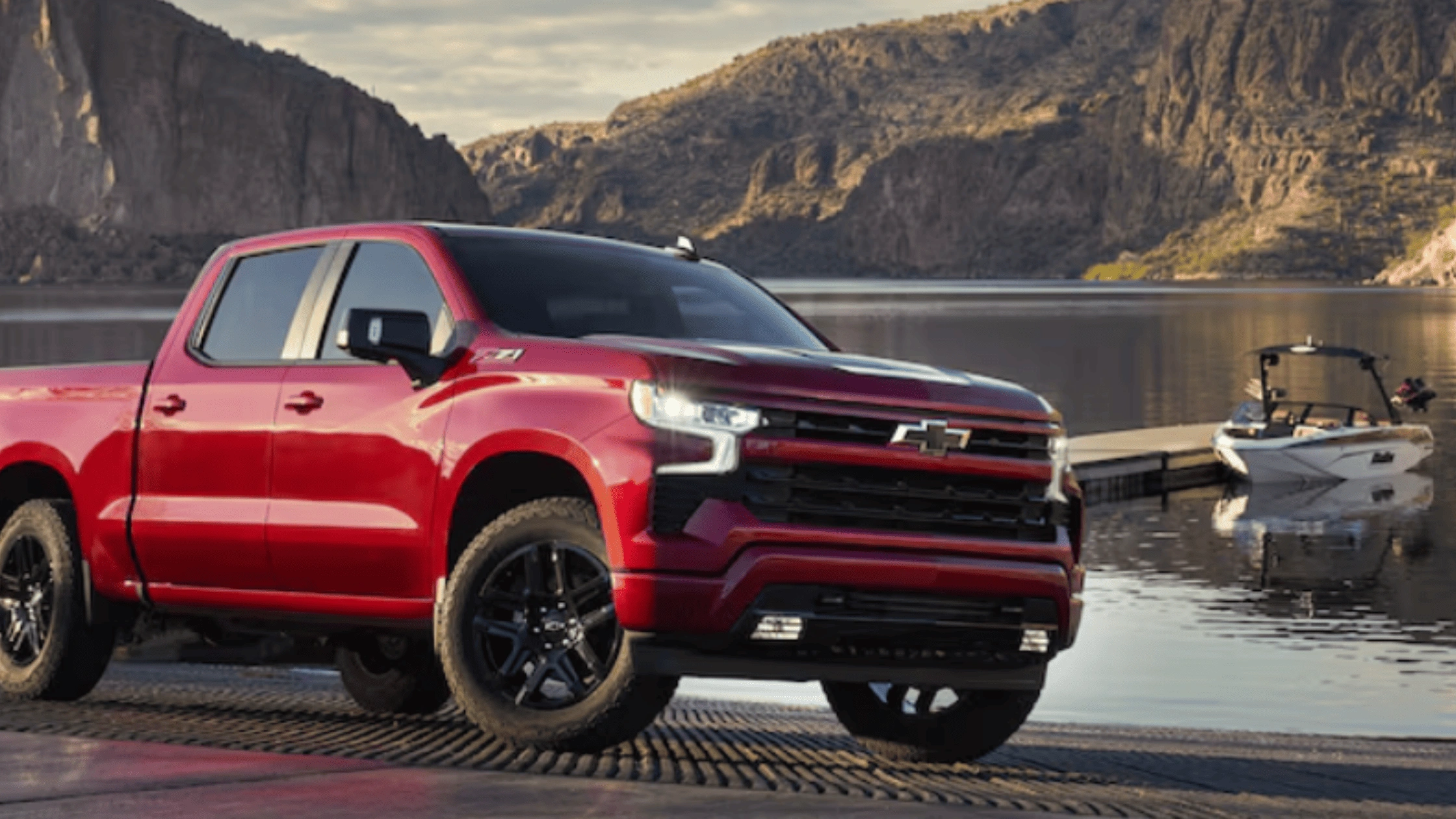 2026 Chevrolet Silverado in bright red parked near a lake with a boat docked, showcasing durability and versatility near Fort Bragg, NC.