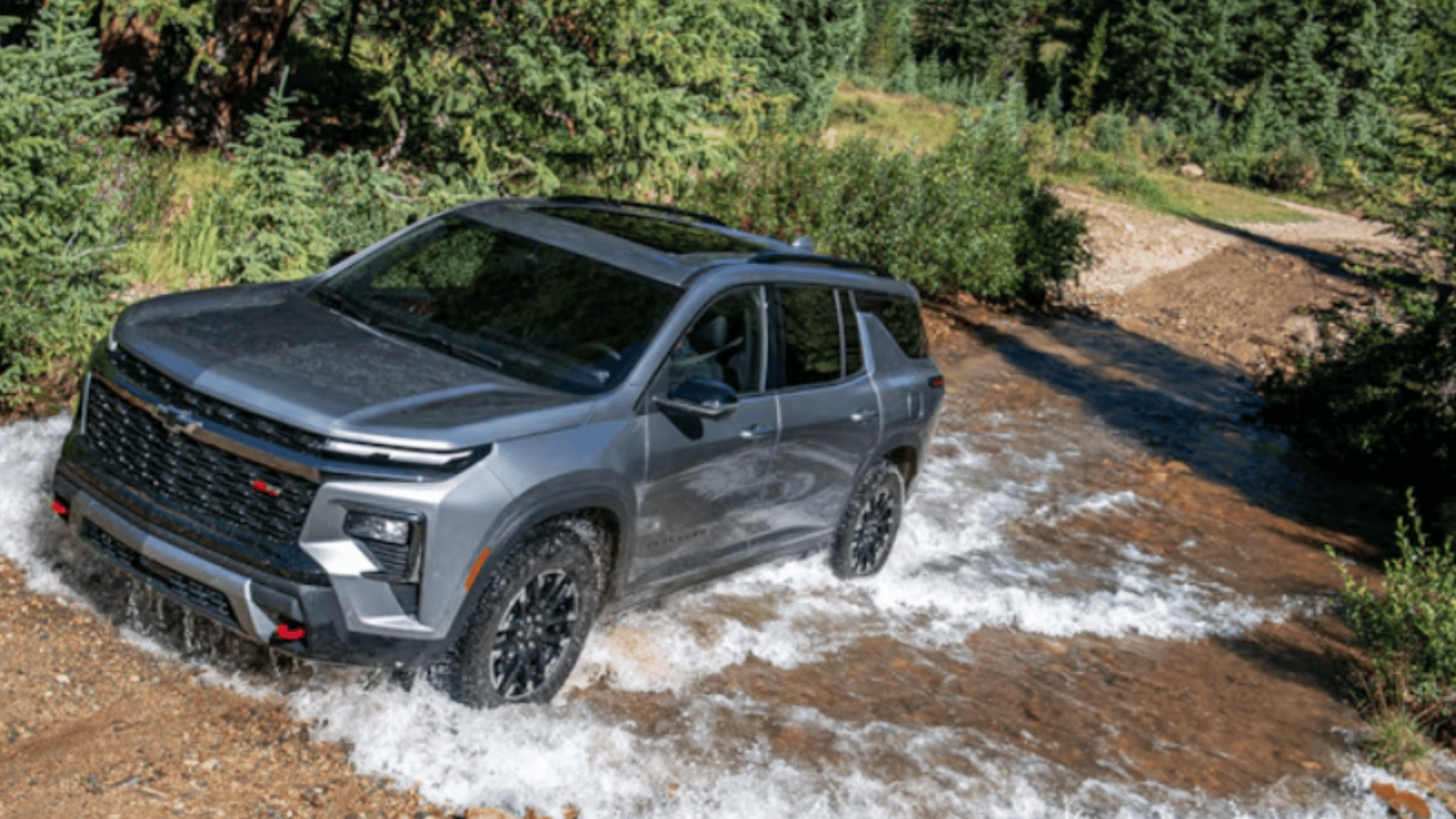 2026 Chevrolet Traverse in gray crossing through water on an off-road trail, highlighting rugged capability near Fort Bragg, NC.