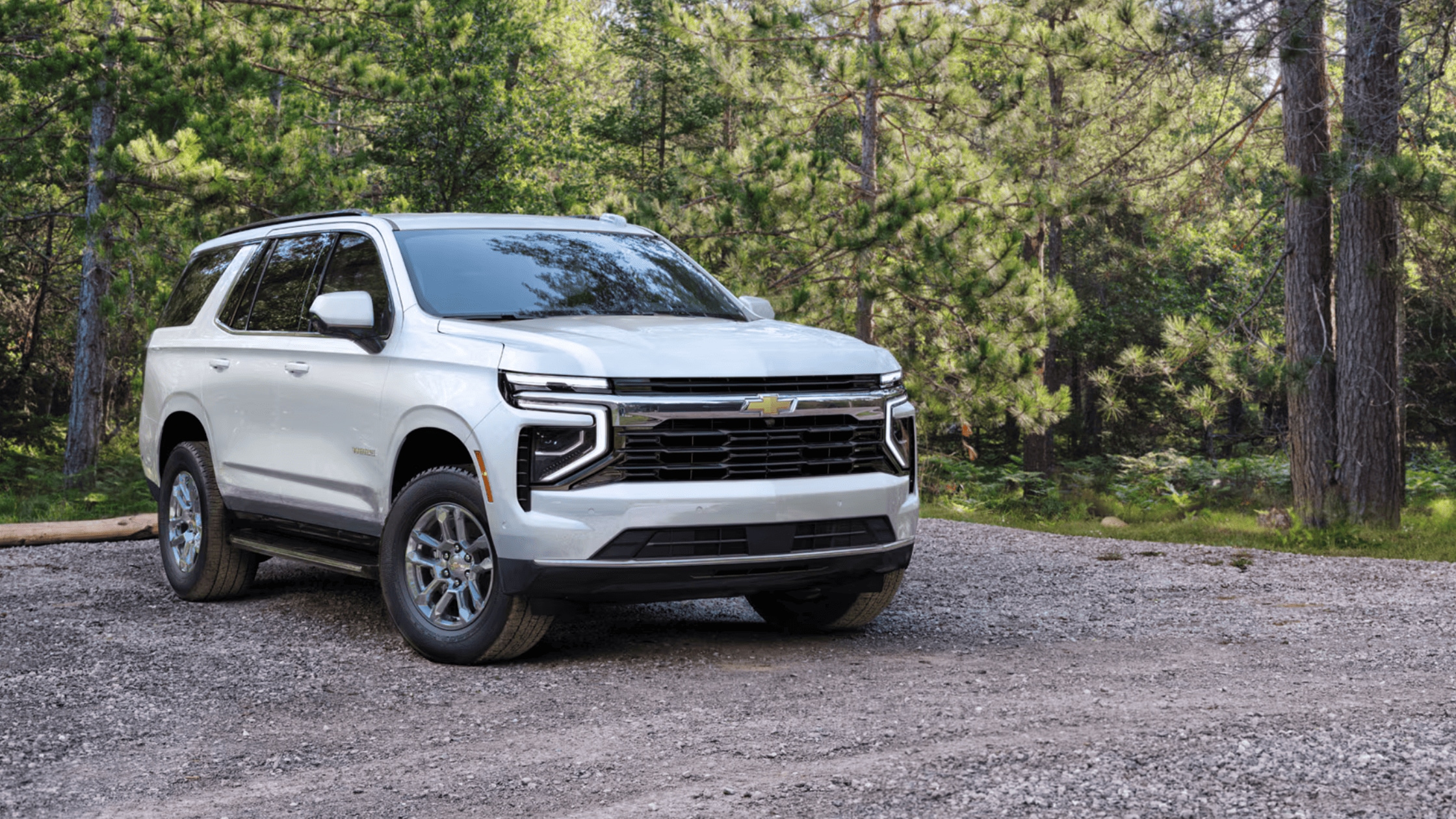 2025 Chevrolet Tahoe in white parked in a wooded area, highlighting its advanced safety features and smooth ride for Fayetteville drivers.