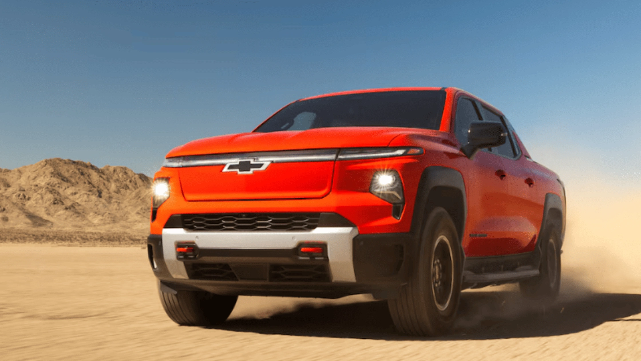 2025 Chevrolet Silverado EV truck kicking up dust on rugged terrain near Fort Bragg