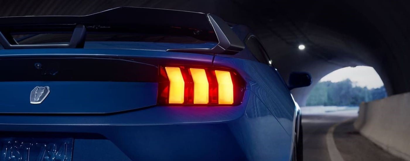 A close up of the passenger side taillight on a blue 2024 Ford Mustang Dark Horse in a tunnel.