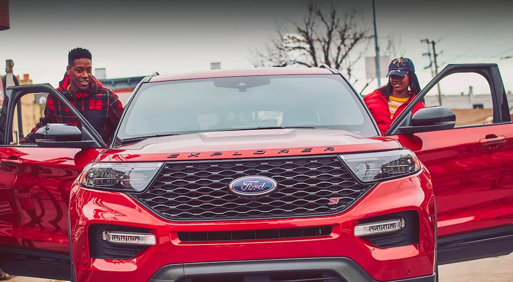 People getting into a red 2023 Ford Explorer ST at a gas station.