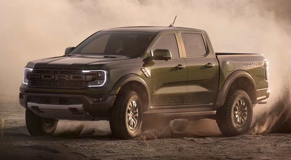 A green 2024 Ford Ranger Raptor kicks up dust while off-roading.