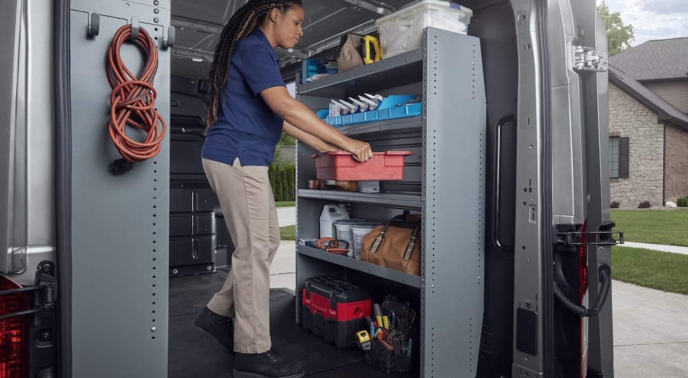 A woman organizing tools inside of the back of a 2023 Ford Transit.