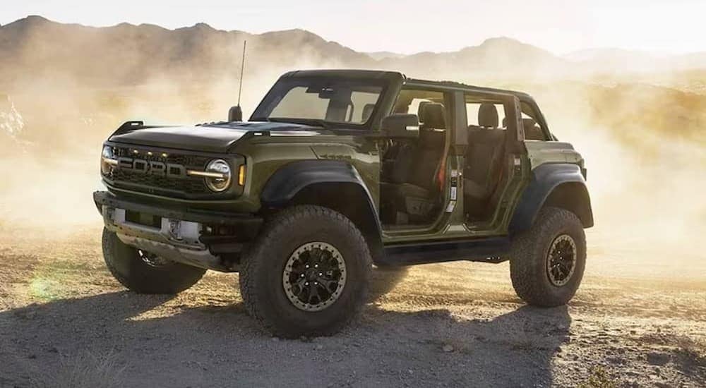 A green 2024 Ford Bronco Raptor parked on a dusty trail.