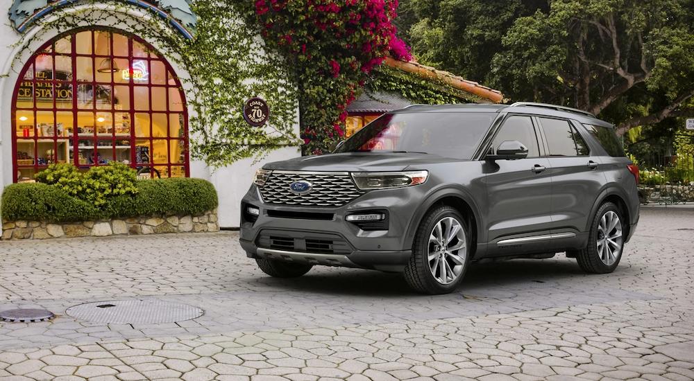 A silver 2023 Ford Explorer Platinum for sale parked in front of lush greenery.