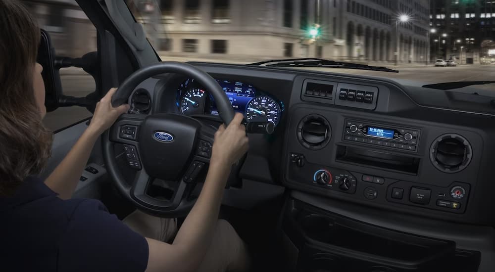 A woman test driving a 2025 Ford E-Series Cutaway on a city street.