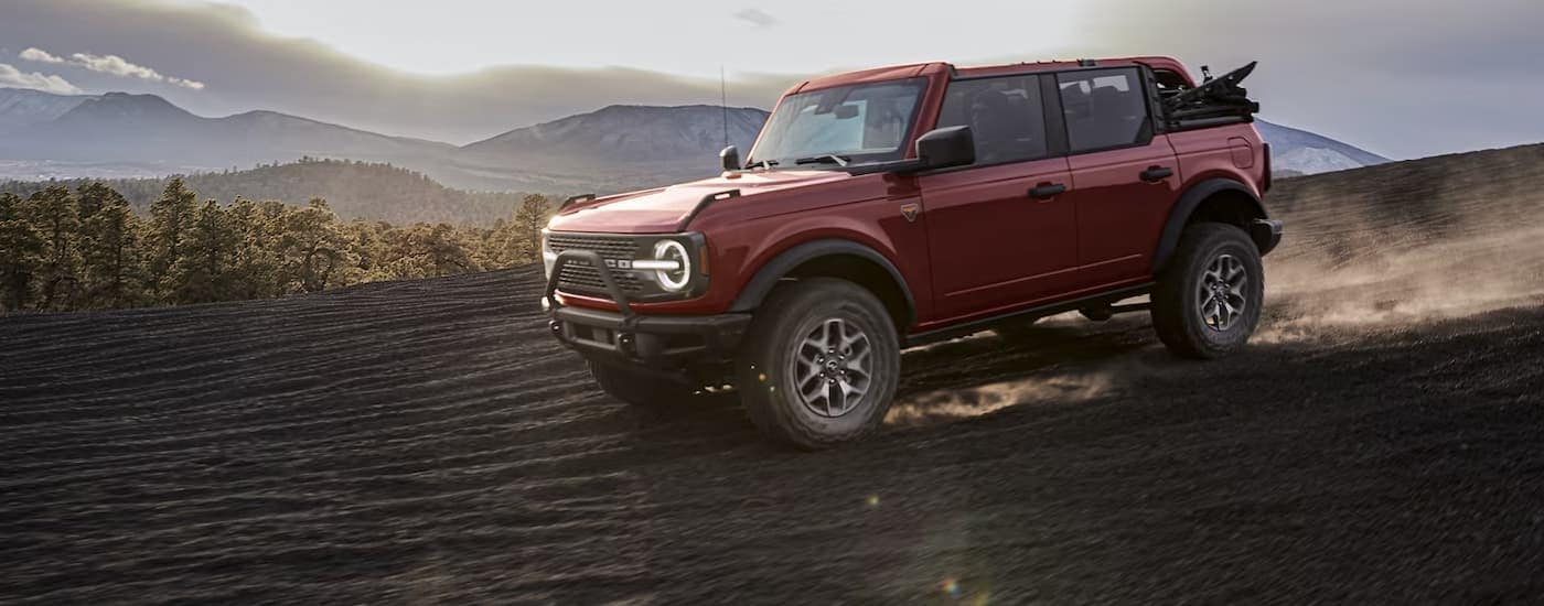 A red 2024 Ford Bronco Badlands off-roading on a sandy mountainside.