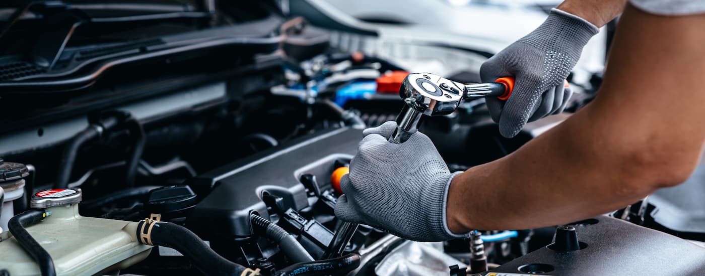 A car mechanic is shown working on an engine.