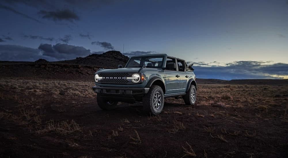 A blue 2024 Ford Bronco Badlands parked in an open desert at dusk.