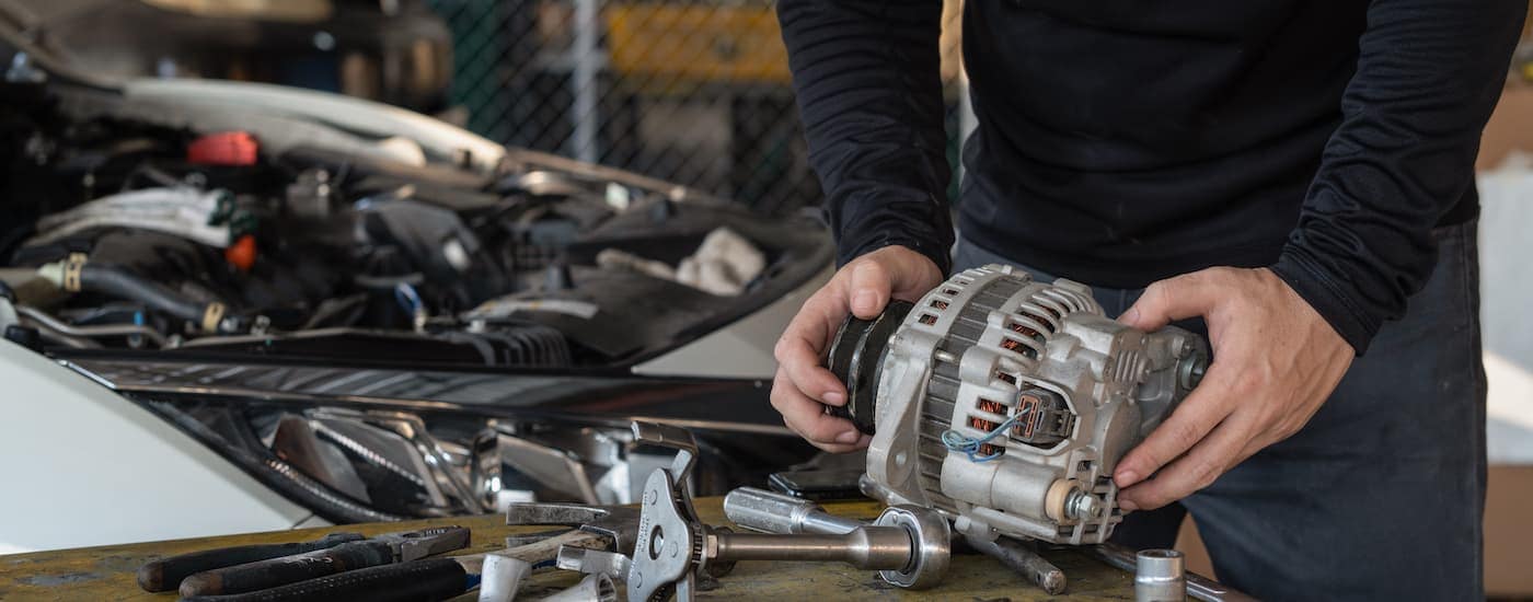 A mechanic is shown repairing an alternator at a Ford service center near Queens.