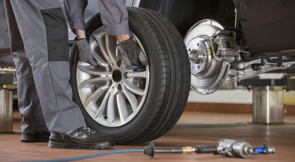 A technician is shown replacing a wheel at a Ford service center near Queens.