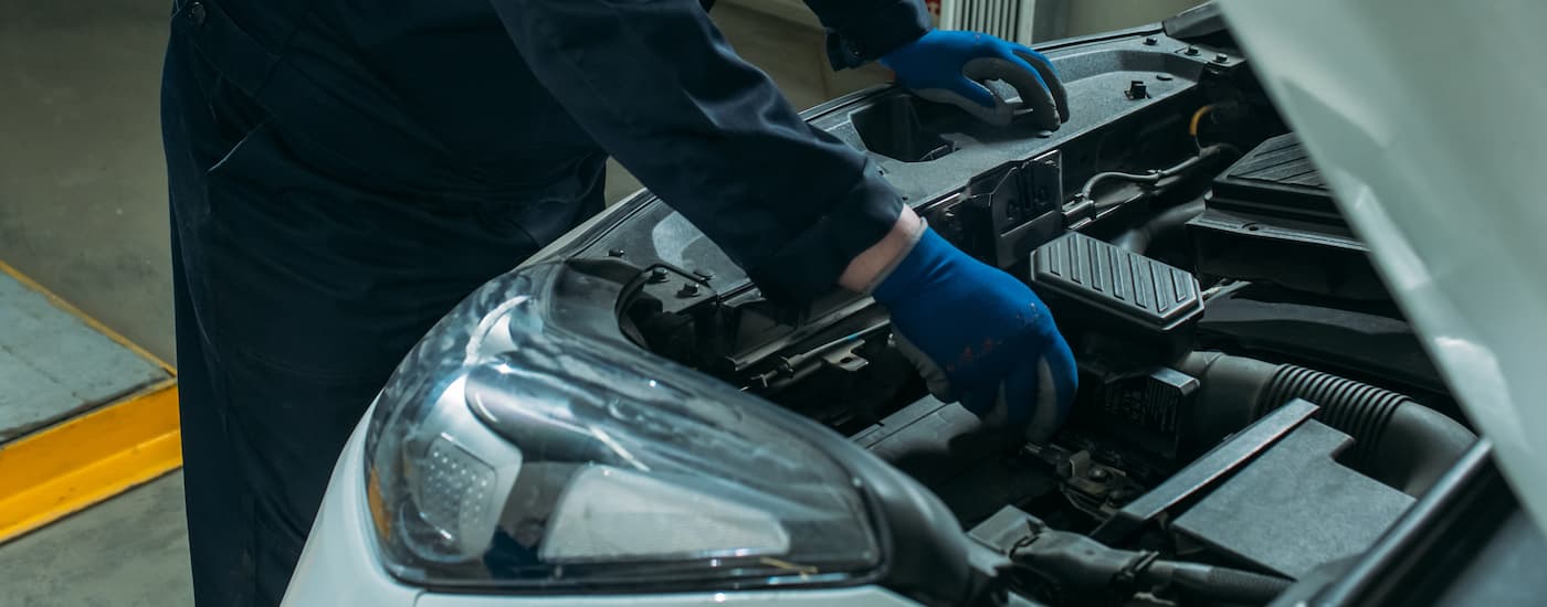 A mechanic working on a car battery at a Ford service center near Hempstead.