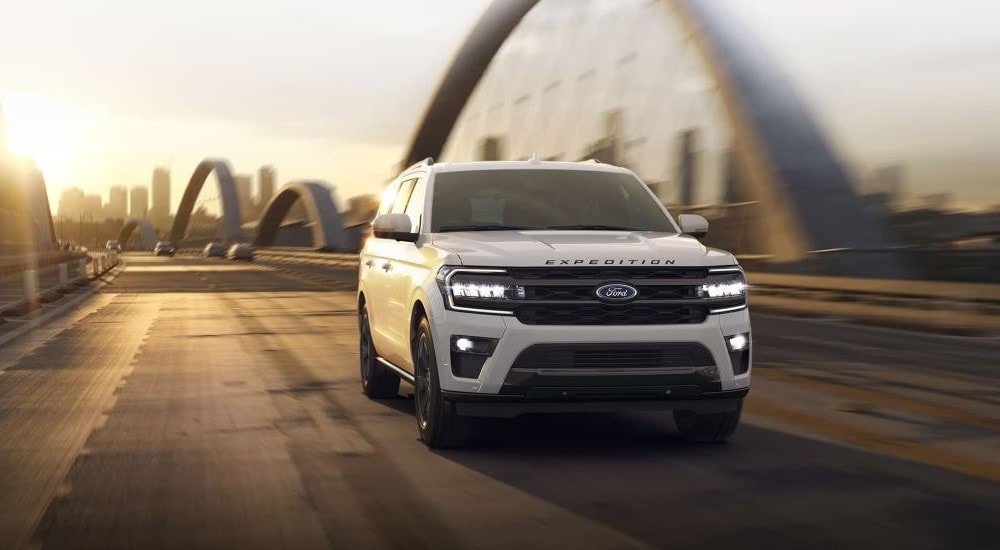 A white 2024 Ford Expedition driving over a large bridge after visiting a Ford dealer.